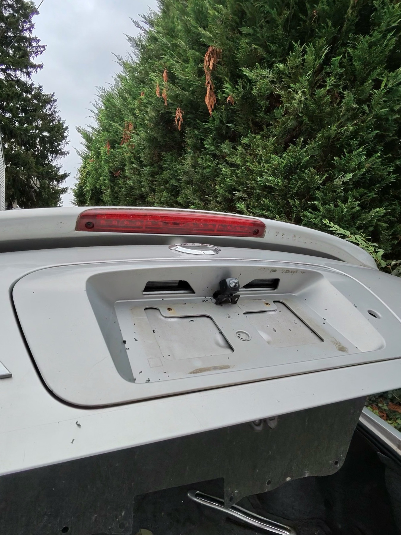 Backup camera mounted above the Nissan rear license-plate location with no plate visible